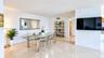 Open-concept dining area featuring polished stone tile flooring, neutral wall finishes, and a decorative wall-mounted mirror