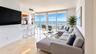 Open-concept interior featuring large-format tile flooring, floor-to-ceiling windows, an integrated kitchen breakfast bar, and a balcony with expansiv