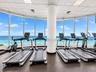 Fitness center featuring floor-to-ceiling panoramic windows, ocean horizon exposure, and a central structural column