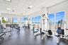 Fitness center featuring floor-to-ceiling windows, ocean horizon backdrop, drop-ceiling grid, and durable rubberized flooring