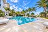 Swimming pool with stone-tiled deck, integrated spa, and surrounding palm trees