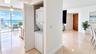 In-unit laundry closet featuring white louvered folding doors, floor-to-ceiling glass paneling, tile flooring, and a solid-core wood entry door