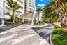 Building exterior featuring a geometric steel-frame portico, multi-toned paved driveway, and curated tropical landscaping