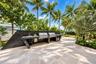 Outdoor kitchen featuring a sleek, dark-veined stone countertop, built-in stainless steel dual grills, an integrated stainless steel sink, and light-t