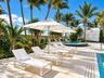 Outdoor pool area featuring natural stone decking, a circular jetted spa, and mature palm landscaping