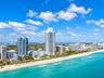 Aerial perspective of coastal high-rise towers positioned along a sandy shoreline with direct oceanfront exposure