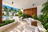 Covered patio featuring large-format stone tile flooring, vertical wood-panel accent wall, integrated recessed lighting, and built-in curved stone pla