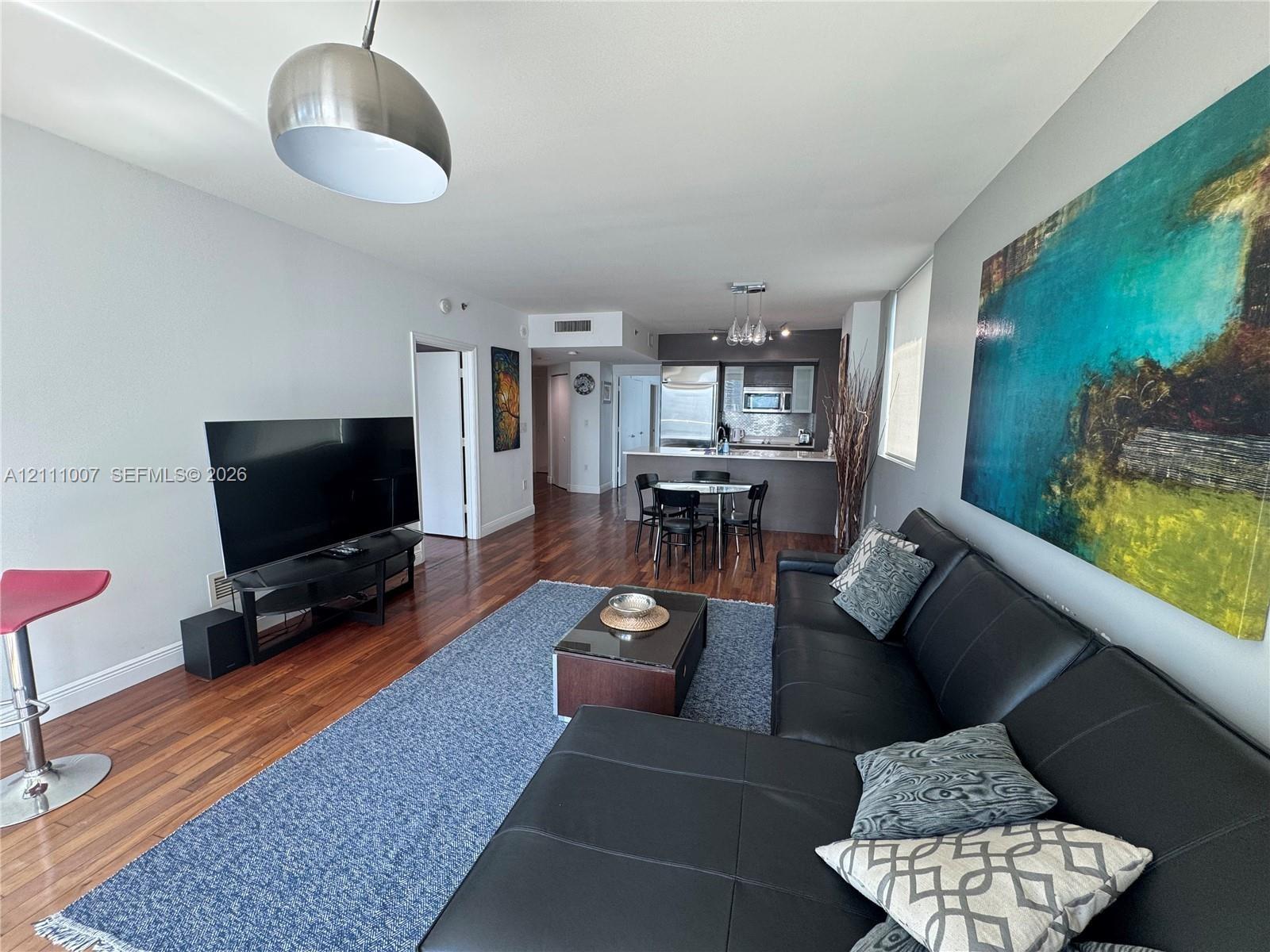 Open-concept interior featuring wood-finish flooring, a kitchen island, recessed lighting, and a brushed-metal dome pendant fixture