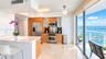 Kitchen featuring wood-finish cabinetry, stainless steel appliances, stone-topped island, polished tile flooring, and floor-to-ceiling glass sliding d