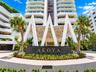 High-rise building featuring a geometric canopy entrance, stone-finished signage, curved balcony detailing, and a paver stone circular driveway