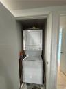 Stacked white laundry unit housed in a dedicated closet