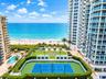 High-rise property featuring a private tennis court, outdoor swimming pool, manicured lawn area, and tiered balconies