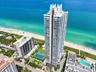 High-rise oceanfront tower featuring tiered architectural design, expansive balconies, a dedicated tennis court, and on-site swimming pools