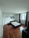 Bedroom featuring dark wood-finish flooring and a window with neutral-toned curtains