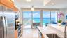 Kitchen featuring light-finish cabinetry, stone countertops, stainless steel appliances, polished tile flooring, and floor-to-ceiling glass doors open