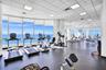Fitness center featuring expansive floor-to-ceiling windows, panoramic ocean scenery, durable rubber flooring, and a suspended drop-tile ceiling