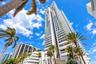 High-rise tower featuring a white concrete facade, recessed glass-paneled balconies, and architectural structural elements