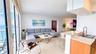 Open-concept living space featuring floor-to-ceiling windows, natural stone flooring, kitchen peninsula with a quartz countertop, and recessed lightin