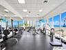 Fitness center featuring floor-to-ceiling windows, full-wall mirrors, rubberized flooring, and drop-ceiling tiles