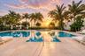 Swimming pool with a raised circular spa, expansive stone-paver pool deck, and mature palm tree landscaping
