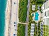Oceanfront property featuring direct beach access, a rectangular swimming pool, a separate circular spa, paved pedestrian pathways, and lush tropical 