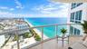 Private balcony featuring polished stone flooring and glass panel railings with an unobstructed coastal panorama