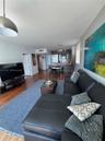 Open-concept living space featuring wood-finish flooring, recessed lighting, and a kitchen equipped with a breakfast bar and stainless steel appliance
