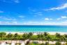 Oceanfront setting with a sandy beach, turquoise water, mature palm trees, and coastal horizon