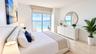 Polished stone flooring, floor-to-ceiling sliding glass doors, and a private balcony overlooking the ocean