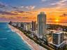 Aerial coastal location featuring direct ocean frontage, expansive shoreline access, and proximity to major high-rise development