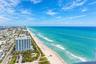 Aerial perspective of the coastline featuring expansive ocean frontage, sandy beaches, and high-rise structural density