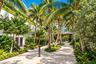 Landscaped courtyard featuring stone paving, mature palm trees, integrated green walls, and a covered pavilion