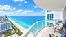 Covered balcony featuring natural stone flooring, glass panel railings, and expansive ocean scenery