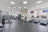 Fitness facility featuring rubberized flooring, recessed grid lighting, multiple treadmills, and wall-mounted televisions