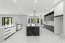Modern kitchen featuring flat-panel cabinetry, a central island with a contrasting stone finish, stone-surface countertops, tile flooring, and a stain