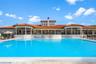 Swimming pool with paved surround, covered terrace, and Mediterranean-style architecture featuring a tile roof