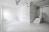 Finished garage space featuring large-format tile flooring, a staircase with matching tile risers and treads, recessed lighting, and white wall finish