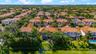Aerial perspective featuring tile-roofed residences, landscaped grounds with mature palm trees, and waterfront perimeter
