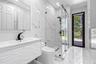 Bathroom featuring floor-to-ceiling porcelain tile, a glass-enclosed walk-in shower with matte black fixtures, a textured vanity cabinet, and a recess