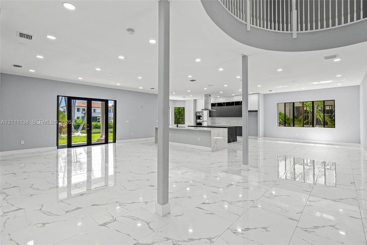 Open-concept interior featuring large-format stone-finish flooring, recessed lighting, a kitchen island with stone-finish countertop, structural suppo