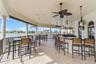 Covered patio featuring stone-finish flooring, built-in stone bar with a dark countertop, ceiling-mounted fans, decorative pendant lighting, and stone