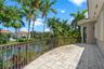 Covered balcony featuring stone tile flooring, decorative metal railing, and direct water frontage