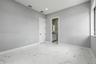 Polished stone-finish flooring with large-format veining, recessed lighting, and a multi-panel door