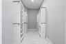 Walk-in closet featuring white built-in shelving, multiple hanging rods, and large-format tile flooring with a neutral vein pattern