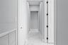 Hallway featuring white veined tile flooring, solid core two-panel doors, and neutral wall tones