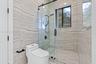Walk-in shower featuring large-format horizontal tile, glass enclosure with matte black hardware, rainfall showerhead, and mosaic tile flooring