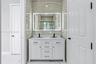 Double vanity featuring a white cabinetry base, stone-look countertop, integrated dual sinks, and matte black widespread faucets, accented by full-hei