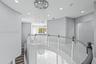 Curved balcony featuring a multi-tiered crystal chandelier, white stone-finish flooring with grey veining, and a white balustrade with a contrasting h