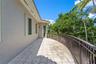 Curved exterior terrace featuring stone-finish tile flooring, a metal railing, and stucco wall construction