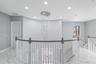 Curved architectural wall featuring a multi-tiered crystal chandelier, polished stone flooring, and a balustrade staircase with wood-finish handrails